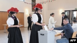 Femei purtând pălării tradiționale „bollenhut", tipice pentru regiunea Pădurea Neagră, votează în alegerile parlamentare la o secție de votare din Gutach, sudul Germaniei, 23 februarie 2025