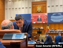Liderul AUR, George Simion, cu spatele la tribuna Parlamentului în timpul răspunsului dat moțiunii Opoziției de premierul Ilie Bolojan.