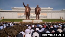 Coreeni se închină în fața statuilor foștilor lideri ai țării: Kim Il Sung și Kim Jong Il.
