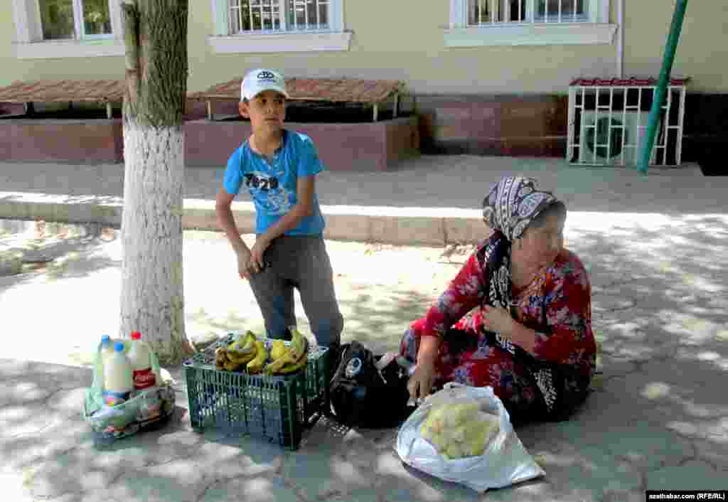 Aşgabadyň "Teke bazarynyň" golaýyndaky köçeleriň birinde ejesi bilen gaýnadylan mekgejöwen, süýt we banan satýan oglanjyk.