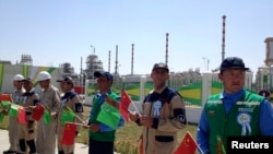 Türkmen we hytaý baýdaklaryny göterip duran nebit-gaz işgärleri. Illýustrasiýa suraty