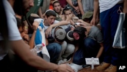 Familia și prietenii a trei adolescenți israelieni răpiți în Cisiordania plâng în timpul înmormântării. 1 iulie 2014. Cadavrele adolescenților au fost găsite după două săptămâni de căutări în Cisiordania și au dus la o agravare a conflictului