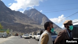 Men wear protective face masks as a preventive measure against coronavirus disease (COVID-19) outbreak as they stand by a queue of vehicles at a check post while entering Gilgit in northern Pakistan on March 22.
