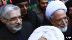 Ирандын оппозициячыл лидерлери Мир Хусейн Мусави (солдо) жана Мехди Карруби (оңдо)  маркум айатолла Хусейн Али Монтазеринин сөөгүн коюу жөрөлгөсү маалында. Ыйык Кум (Ком) шаары. 2009-жылдын 21-декабры. AFP PHOTO/STR.