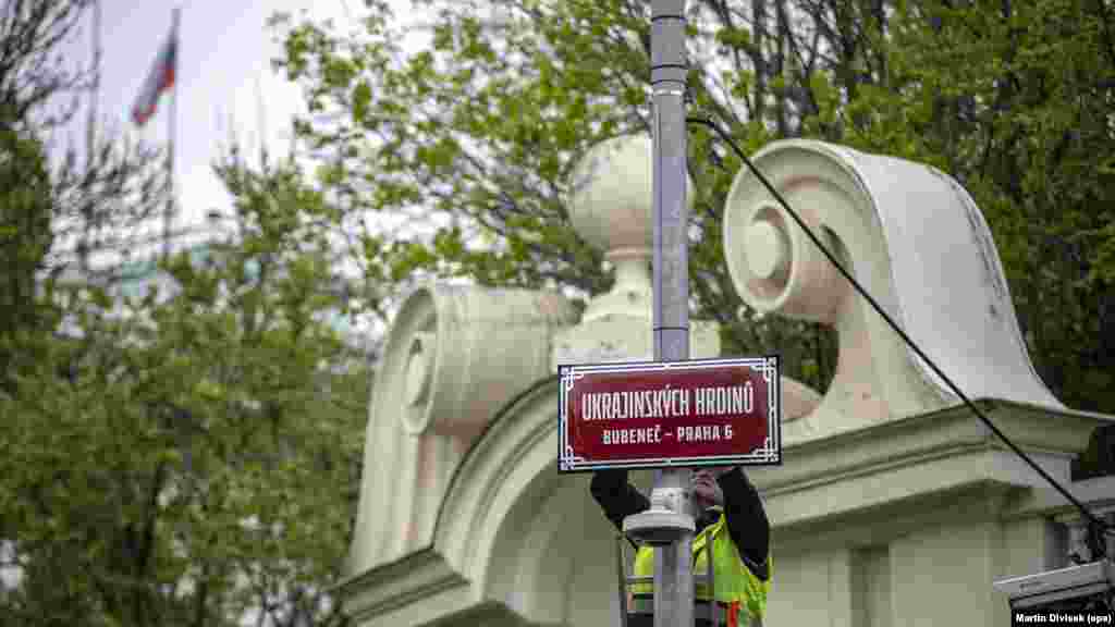 Общински работник монтира табела с името на улица "Украинските герои" на стълб пред руското посолство в Прага, Чехия, април 2022 г.