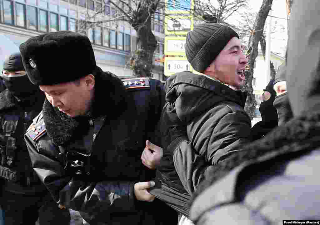 Полиция "Нұр Отан" кеңсесі алдында саяси талап көтерген азаматтардың бірін ұстап жатыр.