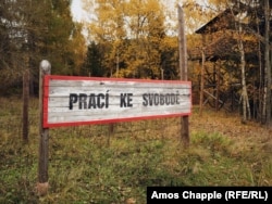 Un semn reconstruit la locul unui lagăr de muncă din Jachymov, pe care scrie „Munca te eliberează”.