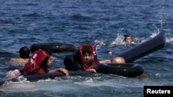 Refugees float as they hold a tube after a dinghy carrying Syrian and Afghan refugees deflated some 100m away before reaching the Greek island of Lesbos on September.