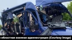A mangled minibus on a road in Ukraine's Sumy region, where Ukrainian authorities say a Russian drone strioke killed nine people on May 17.