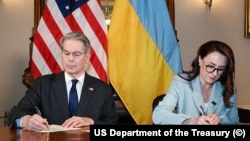Secretarul Trezoreriei SUA, Scott Bessant, și prim-viceprim-ministrul Ucrainei, Iulia Sviridenko, semnează acordul privind mineralele.