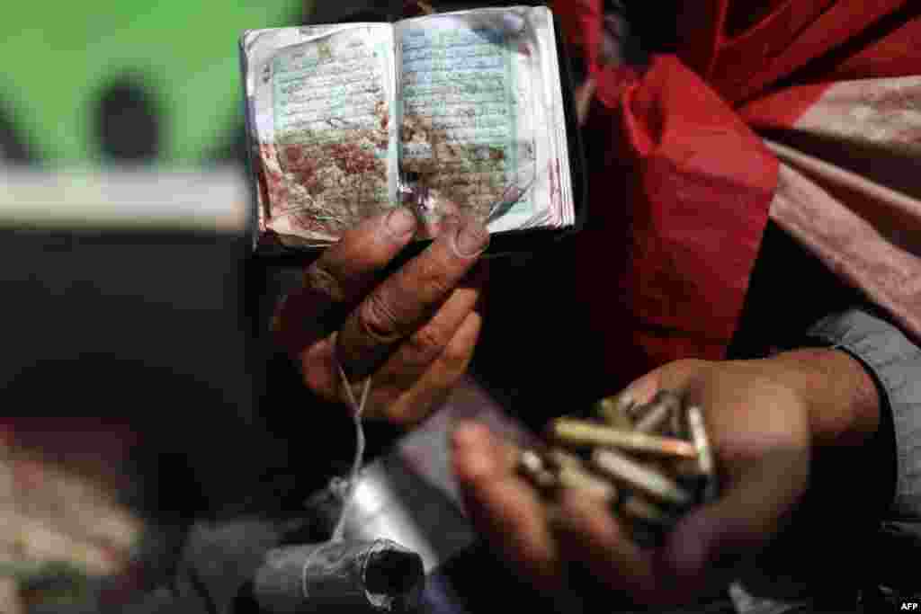 An Egyptian supporter of deposed President Muhammad Morsi holds a copy of the Koran stained with blood and empty casing as he attends a rally in support of the former Islamist leader outside Cairo's Rabaa al-Adawiya Mosque. (AFP/Mahmud Hams)