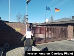 Пикетчик у ворот посольства ФРГ демонстрирует конверт с обращением к канцлеру и Бундестагу Германии.