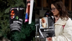 O tânără din Georgia decorează bradul de Crăciun din Tbilisi cu imagini ale persoanelor bătute la proteste