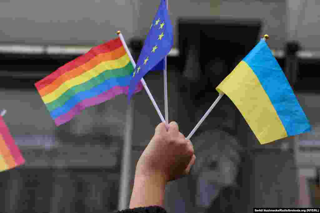 Учасниця Маршу рівності тримає прапори України, ЛГБТК та Європейського Союзу