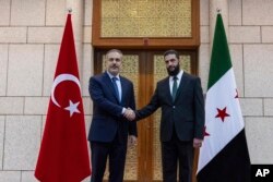 Ministrul turc de externe, Hakan Fidan (stânga), dă mâna cu Ahmad al-Sharaa (dreapta), cunoscut anterior sub numele de luptă Abu Mohammed al-Golani, în timpul întâlnirii lor de la Damasc, Siria, 22 decembrie 2024.
