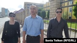 Гражданские активисты Гульзада Исмурзиева, Макс Бокаев (в центре) и Ерлан Башаков у ограждения вокруг здания прокуратуры Атырау. 17 мая 2016 года.
