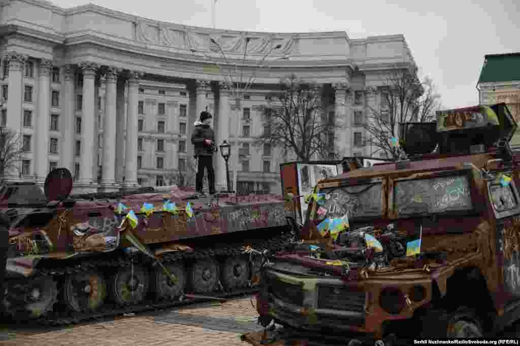 Хлопчык стаіць на зьнішчанай расейскай ваеннай тэхніцы, выстаўленай на Міхайлаўскай плошчы ў Кіеве. Студзень 2025 году