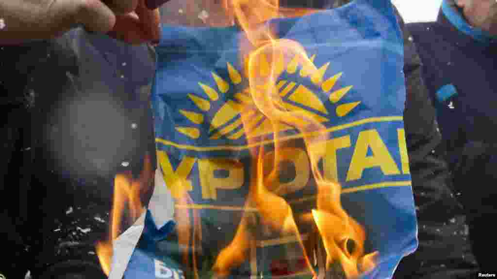 Лидеры казахской оппозиции сжигают предвыборный плакат правящей партии "Нур Отан" после очередной победы этой партии на парламентских выборах. 17 января, Алма-Ата. (Reuters/Шамиль Жуматов)