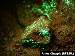 Roci presărate cu autunită radioactivă în interiorul unei mine de uraniu sovietice abandonate. Mineralul strălucește sub lumina unei lanterne UV utilizate pentru identificarea depozitelor radioactive.