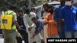 A worker offers hand sanitiser to those maintaining social distancing to buy groceries at a subsidised shop during the nationwide lockdown.