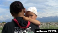 Баласын көтеріп, қоқыстағы уақытша мекенін тастап бара жатқан келіншек. Қоқыстарды төгу мен көму полигоны. Алматы облысы, Қарасай ауданы, 7 маусым  2011 жыл.