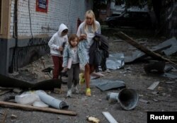 Семейство в близост до жилищна сграда, поразена от руската атака, 28 август 2025 г.