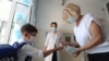 Armenia -- A teacher pours disinfecant onto the hands of a student entering a private school in Yerevan, September 1, 2020.
