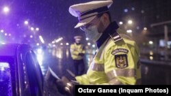 Un polițist, verificând documente, după instalarea restrcițiilor de circulație