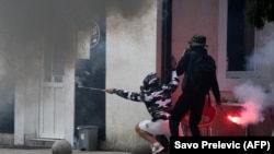 Demonstranti se skrivaju iza zida tokom sukoba nakon protesta protiv ustoličenja Joanikija na Cetinju, 5. septembra 2021. godine