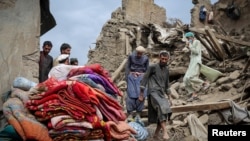 Bărbați afgani pe ruinele unei case distruse în urma cutremurului cu magnitudinea de 6 grade care a lovit estul Afganistanului.