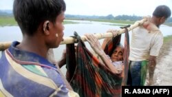 Rohingya refugees carry an elderly woman from Rakhine state in Myanmar along a path near Teknaf in Bangladesh on September 3.