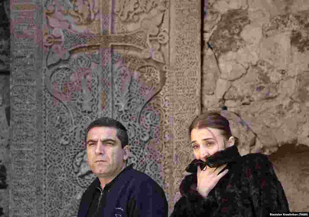A couple walk in front of the monastery's cross stones.