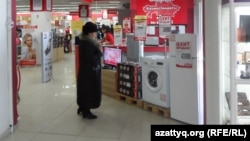 Посетительница магазина разглядывает  бытовую технику. Архивное фото
