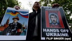 Демонстрант тримає антипутінські банери під час акції протесту проти агресії Росії щодо України перед посольством Росії в Чехії. Прага, 17 квітня 2014 року