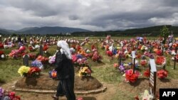 Në grua shqiptare ecën mes varreve të viktimave të masakrës së Mejës. Foto nga arkivi.
