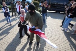 Невядомы ў масцы і зялёнай форме без апазнавальных знакаў забірае сьцяг Ніны Багінскай сёньня на Камароўцы