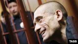 Russian artist Pyotr Pavlensky gestures inside a defendants' cage during a court hearing in Moscow in February.