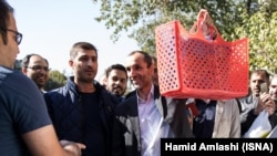 حمید بقایی معاون احمدی نژاد در جریان حضور خود در دادگاه از زنبیلی قرمز برای حمل وسایل خود استفاده می کند. 