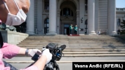 Snimatelj ispred Skupštine Srbije u Beogradu, u novim uslovima, sa zaštitnom maskom i rukavicama obaveznim sredstvima za rad nakon proglašenja pandemije. Zabeleženo 28. aprila 2020.