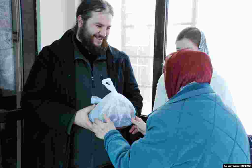 Прихожанка преподносит пакет с едой священнику Никольского собора Вячеславу Пугачеву. Фестиваль постной кухни в Алматы.
