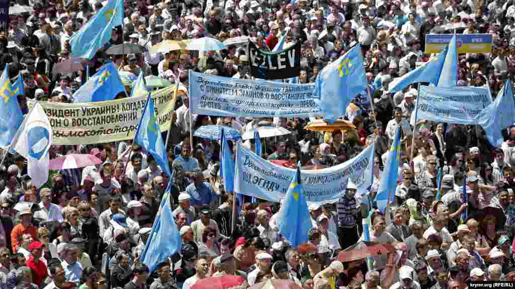 2011 senesi. Qırımtatar ve ukrain bayraqları arasında halqnı ükümetke talaplarınen transporantlar