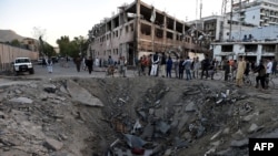 Afghan security forces and residents stand near the crater left by a truck bomb attack in Kabul on May 31.