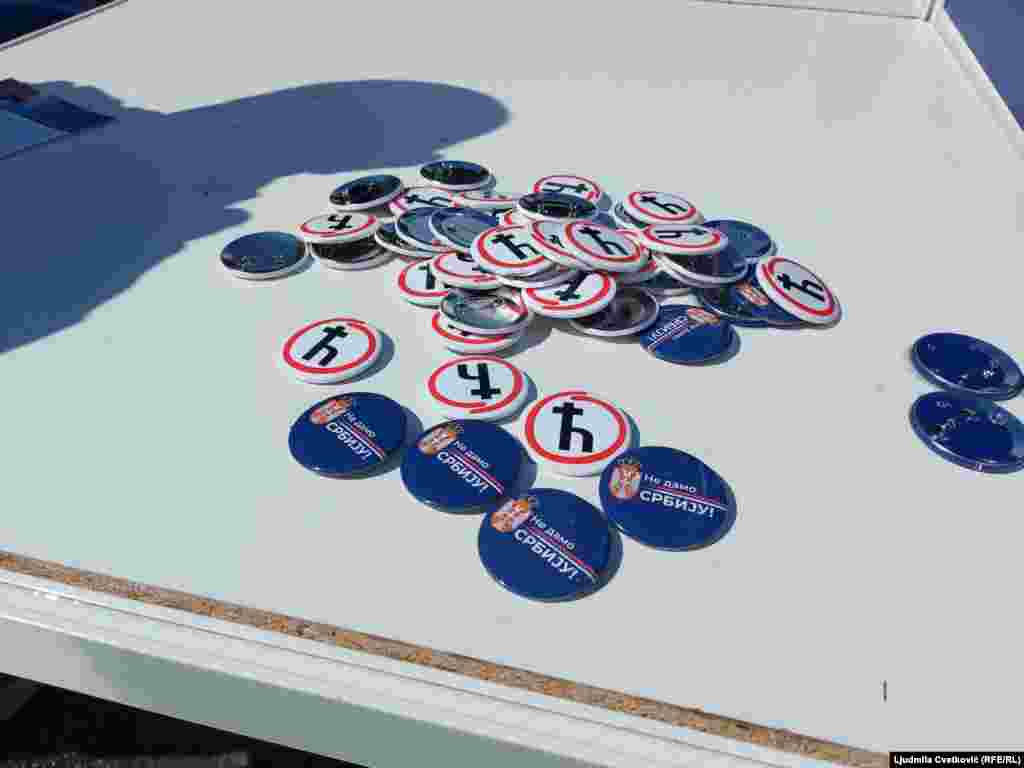 Bedževi sa ćiriličnim slovom "Ć" na štandu naprednjaka, kao aluzija da podržavaju studente koji se protive blokadama fakulteta, a koje opozicioni deo javnosti zove "Ćaci".