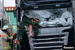 A firefighter stands beside a truck that plowed through a crowded Christmas market in Berlin. At least 12 people were killed.