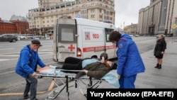 Врачи "скорой помощи" везут пожилую женщину с автобусной остановки в больницу в центре Москвы, 17 апреля 2020 года