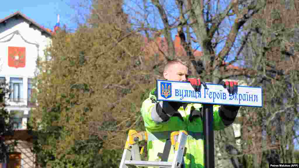 Общински работник монтира табела на украински език с името на улица "Украинските герои" пред руското посолство във Вилнюс, Литва, март 2022 г.