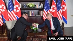 Дональд Трамп и Кич Чен Ын обмениваются рукопожатием