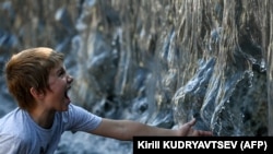 Мальчик охлаждается в фонтане жарким летним днем в центре Москвы 13 июля 2021 года. 