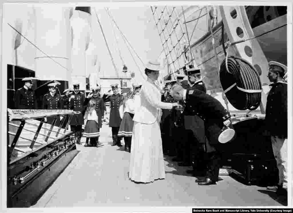 Empress Aleksandra being greeted aboard the Standart, the imperial yacht that served the tsar's family for holidays and official tours. In the background, her young daughters, known as Russia's grand duchesses, are saluted by the crew.
