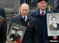 Russian President Vladimir Putin holds the portrait of his father, Vladimir Spiridonovich Putin, as he takes part in the Immortal Regiment march in Moscow.